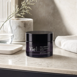 Vie Collection Mela Bright Dark Spot Brightening Cream 50ml on a marble bathroom counter with gypsophila in glass carafe, marble canister, white ceramic tray, white waffle towel and dark cabinetry in background, premium at-home skincare setting