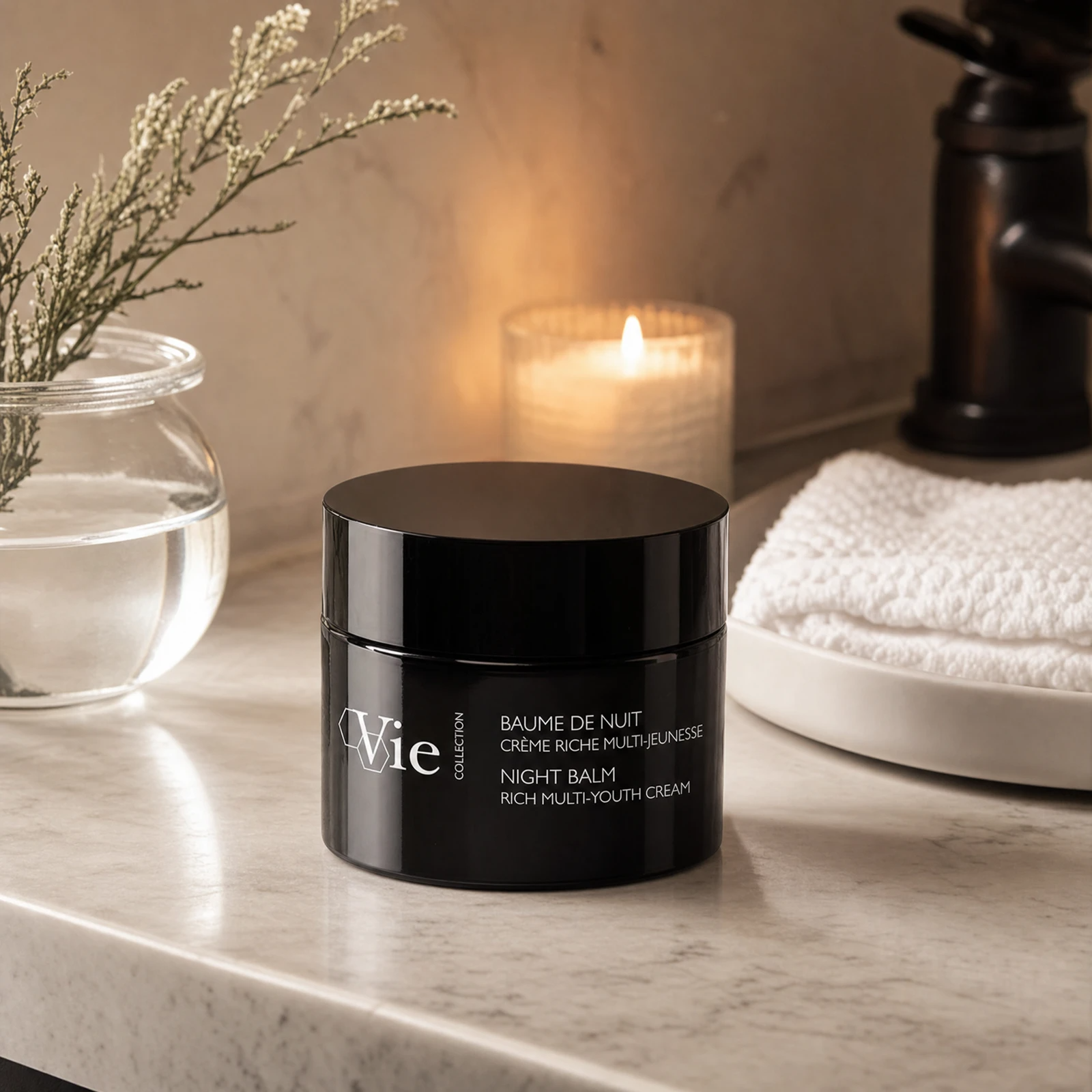 Vie Collection Night Balm Rich Multi-Youth Cream 50g on a marble bathroom counter with dried botanical in glass vase, warm candlelight, white waffle towel on marble tray, premium at-home evening skincare setting