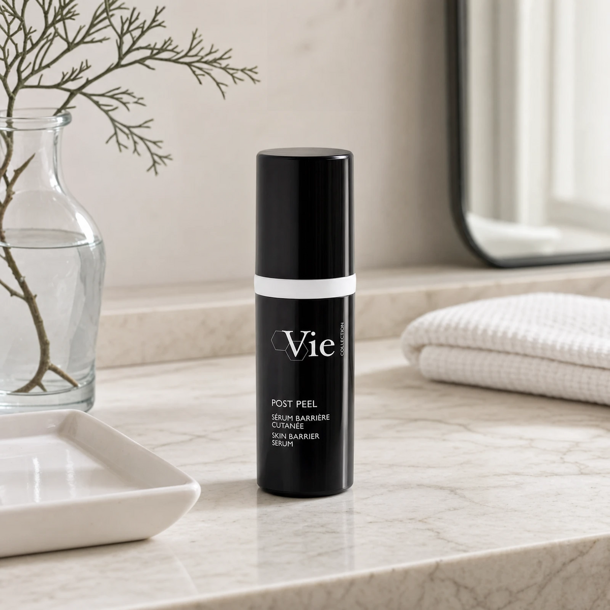Vie Collection Post Peel Skin Barrier Serum 30ml on a marble bathroom counter with dried coral branch in glass carafe, white ceramic tray, stacked white waffle towels and round mirror, premium at-home skincare setting