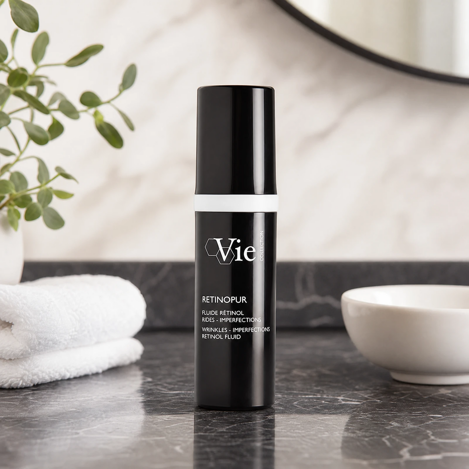 Vie Collection Retinopur Wrinkles Imperfections Retinol Fluid 30ml premium matte-black pump bottle styled on a dark marble vanity with white towels and greenery for Beauty Collective consumer retail.