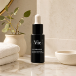 Vie Collection Vita E Ferulic Concentrated Solution 15ml premium matte-black dropper bottle styled on a marble vanity with white towels and greenery for Beauty Collective consumer retail.