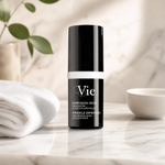 Vie Collection Wrinkle Dimension Hyaluronic Acid Concentrate 15ml premium matte-black bottle styled on a marble vanity with white towels and greenery for Beauty Collective consumer retail.